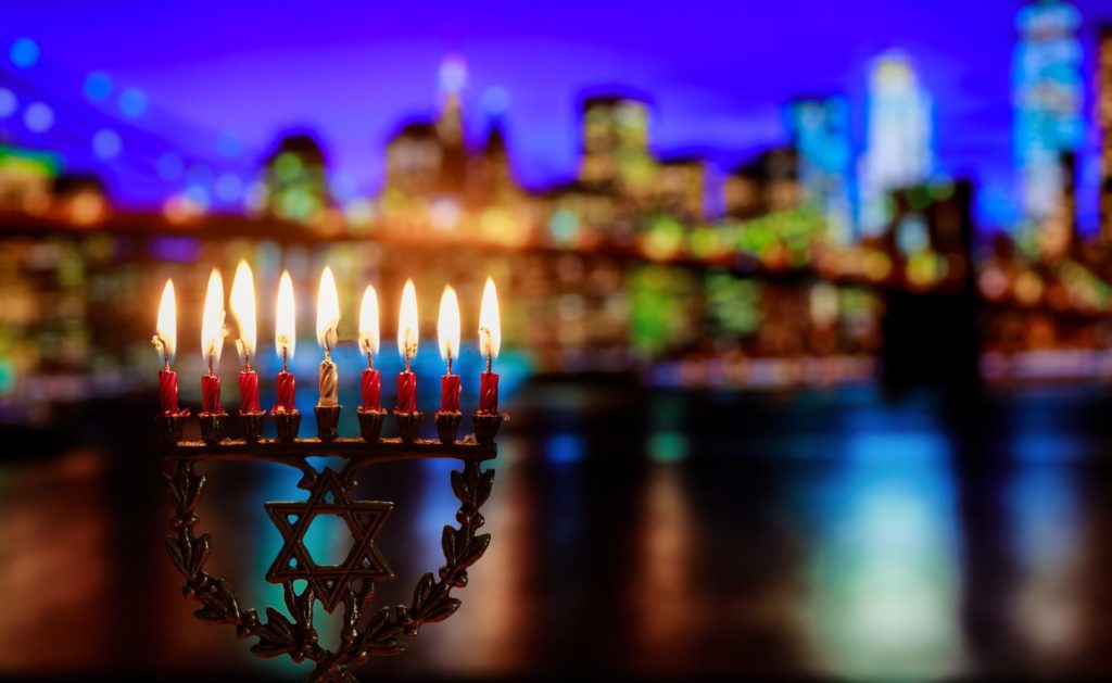 Channukah Menorah overlooking Hudson River and New York City - Couple unwraps red Christmas present with large bow - Unwrap the Gift of Travel - Best Western & AAA Travel